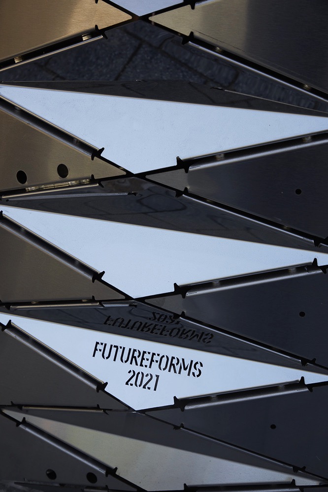 穿孔不鏽鋼表面在日照下形成層次光影，強化作品的金屬生長感。