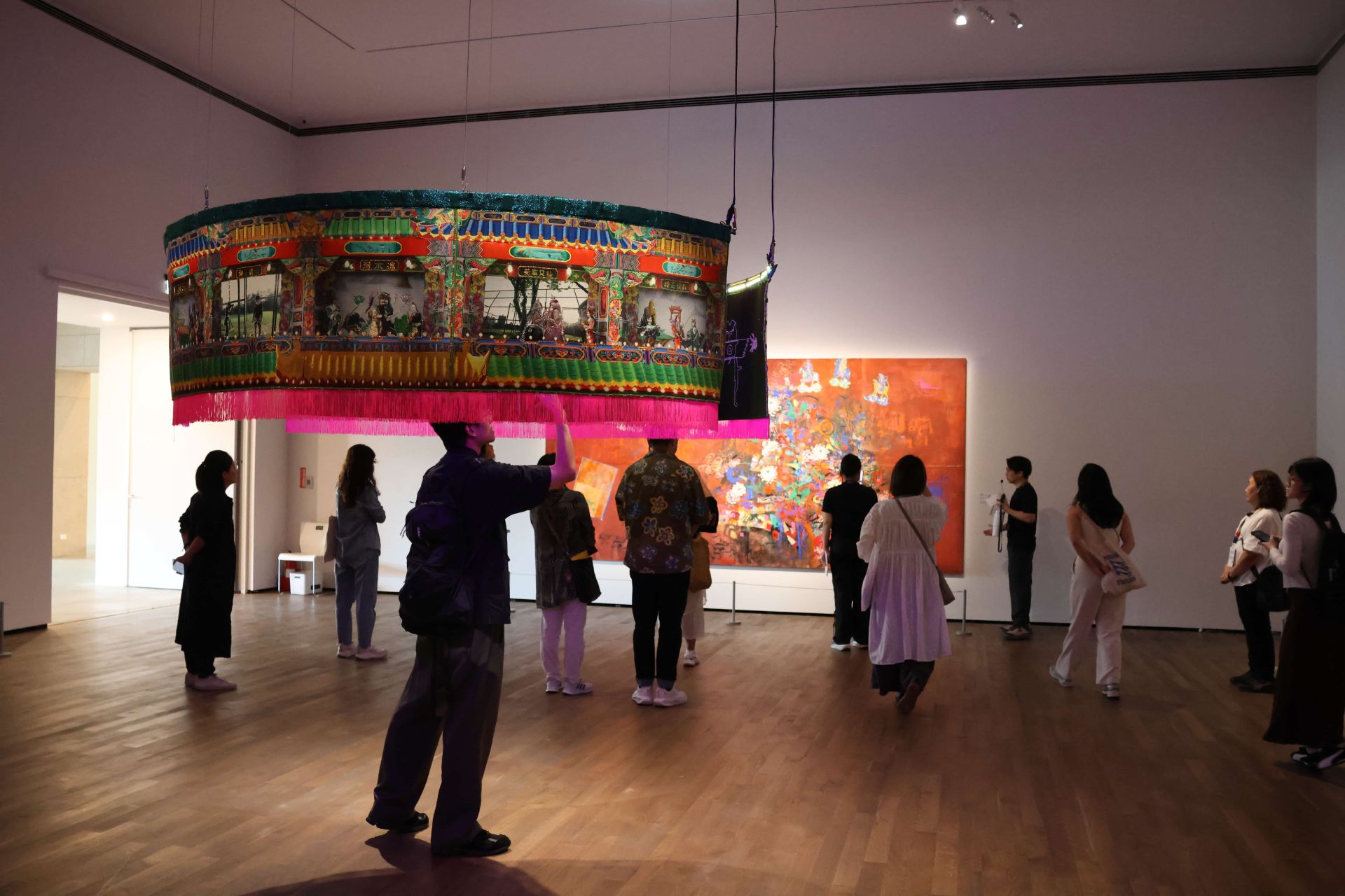 美術館內部展廳展出大型傳統刺繡繡幔與當代繪畫作品，引導觀眾在藝術與空間中漫遊穿梭